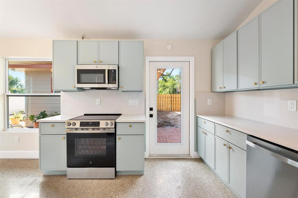 A kitchen with light blue cabinets, stainless steel appliances, and a glass-paneled exterior door — 419 64TH AVENUE S, ST PETERSBURG, FL