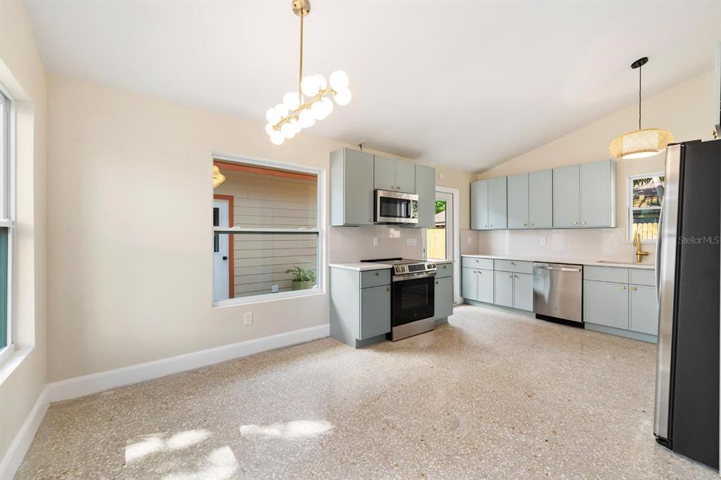 A kitchen with light blue cabinets, stainless steel appliances, and terrazzo flooring — 419 64TH AVENUE S, ST PETERSBURG, FL