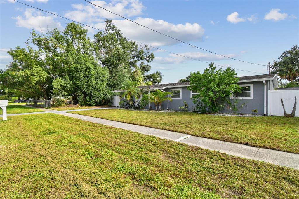 A single-story gray house with a white fence and a sidewalk in the front yard — 4722 W BAY AVENUE, TAMPA, FL