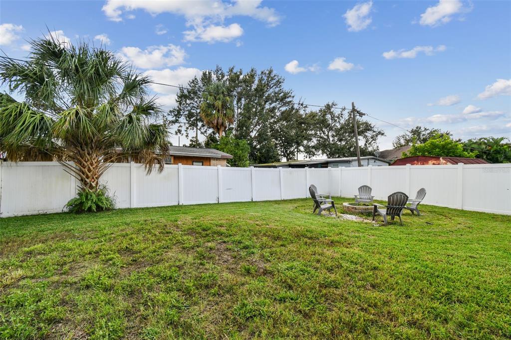 A backyard features a white vinyl fence, a palm tree, and a fire pit area — 4722 W BAY AVENUE, TAMPA, FL