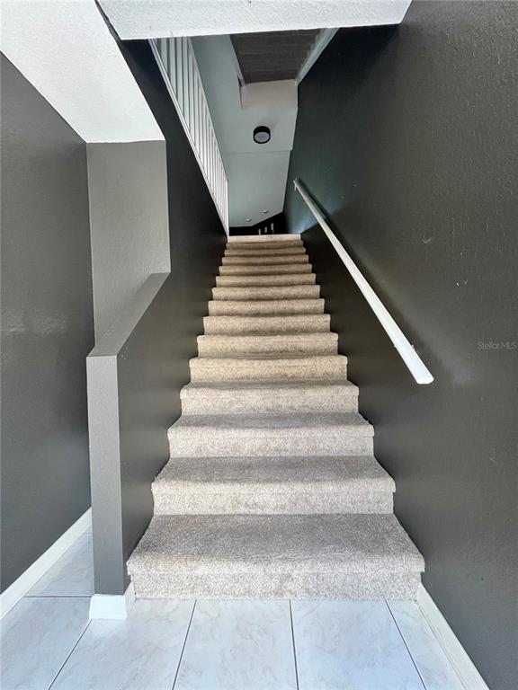 A carpeted staircase with dark gray walls leads to an upper level — 1117 S PINELLAS BAYWAY S UNIT 306, ST PETERSBURG, FL