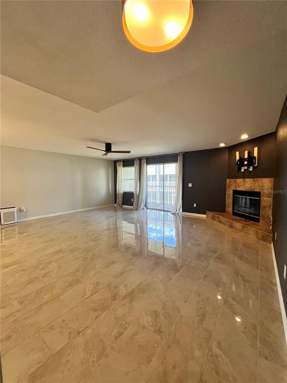 A spacious living room features glossy tile flooring, a fireplace, and a ceiling fan — 1117 S PINELLAS BAYWAY S UNIT 306, ST PETERSBURG, FL