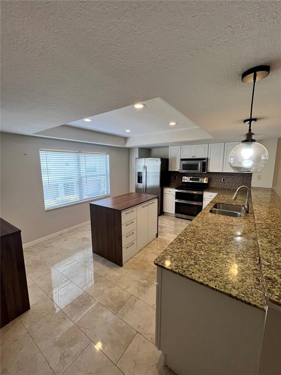 A kitchen features white cabinets, granite countertops, a wood-topped island, and tile flooring — 1117 S PINELLAS BAYWAY S UNIT 306, ST PETERSBURG, FL