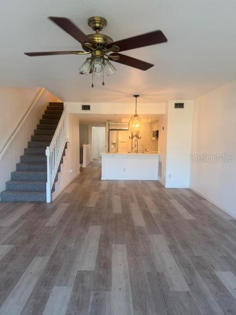 An open-concept living area features wood-look flooring, a ceiling fan, and a staircase with railings — 9978 INDIAN KEY TRAIL # 6 TRAIL, SEMINOLE, FL