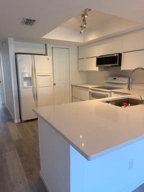 A kitchen features white cabinets, a white refrigerator, and a quartz-topped island with a sink — 9978 INDIAN KEY TRAIL # 6 TRAIL, SEMINOLE, FL