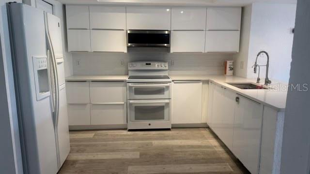 A modern kitchen features white cabinets, stainless steel appliances, and light wood-look flooring — 9978 INDIAN KEY TRAIL # 6 TRAIL, SEMINOLE, FL