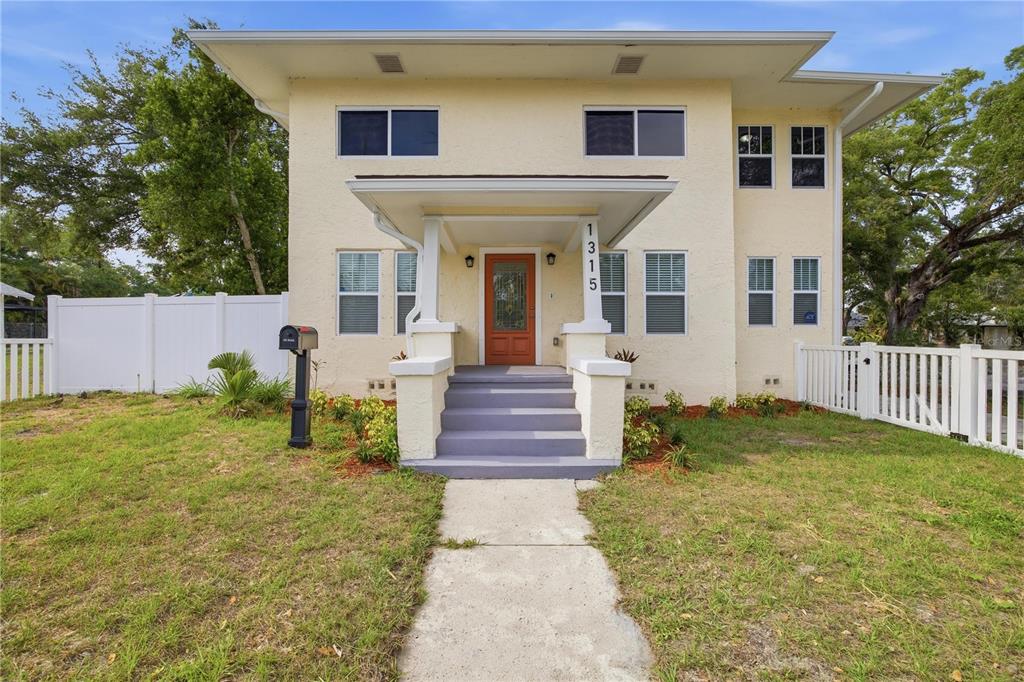 A two-story house with a light yellow exterior, a front porch, and a white fence — 1315 22ND AVENUE S, ST PETERSBURG, FL