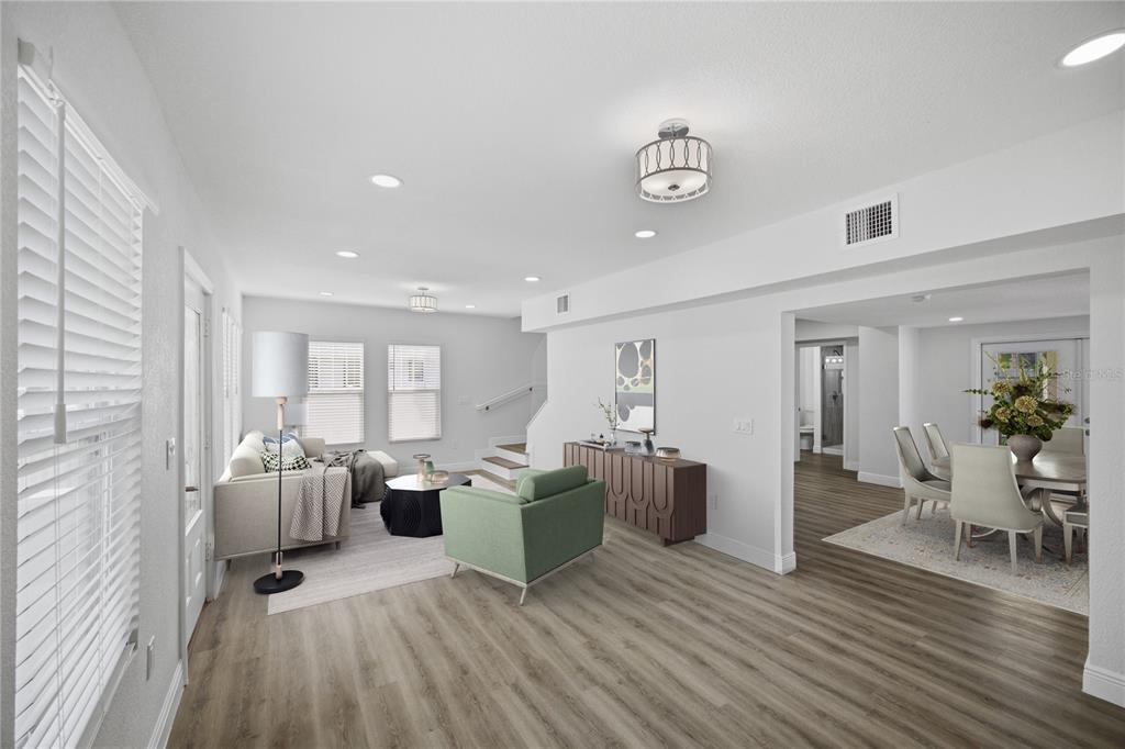 A living room with light wood floors, a green armchair, and an adjacent dining area — 1315 22ND AVENUE S, ST PETERSBURG, FL