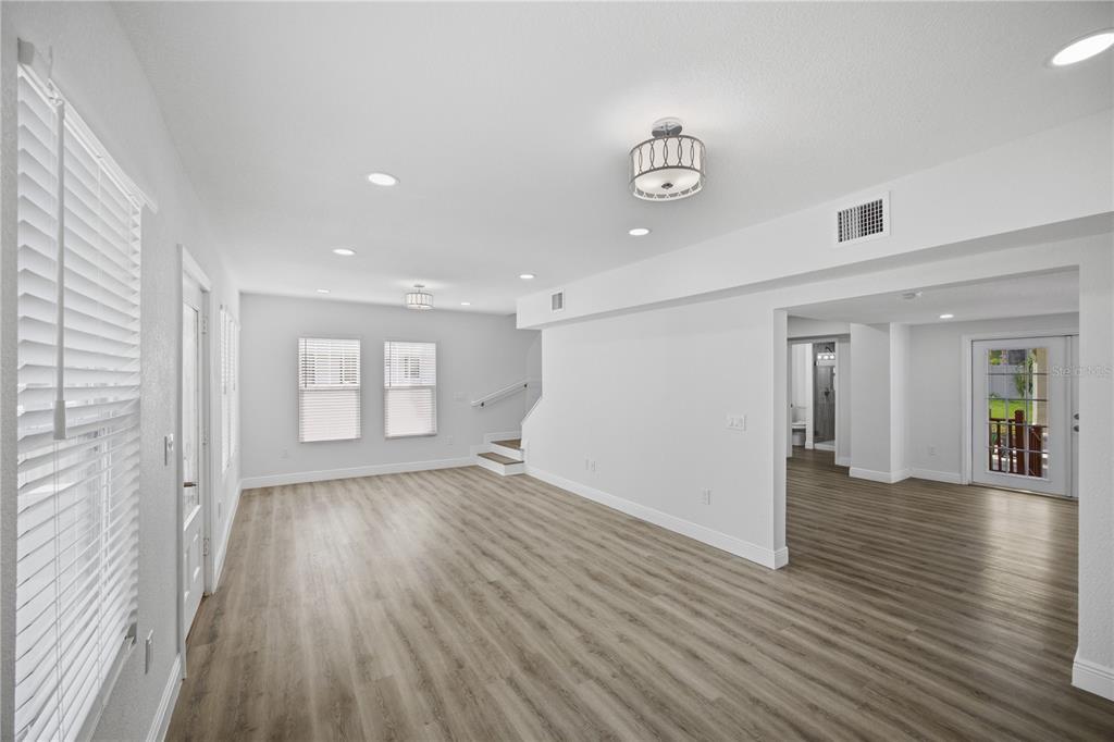 A bright, open-concept living area features light wood-look flooring, white walls, and recessed lighting — 1315 22ND AVENUE S, ST PETERSBURG, FL