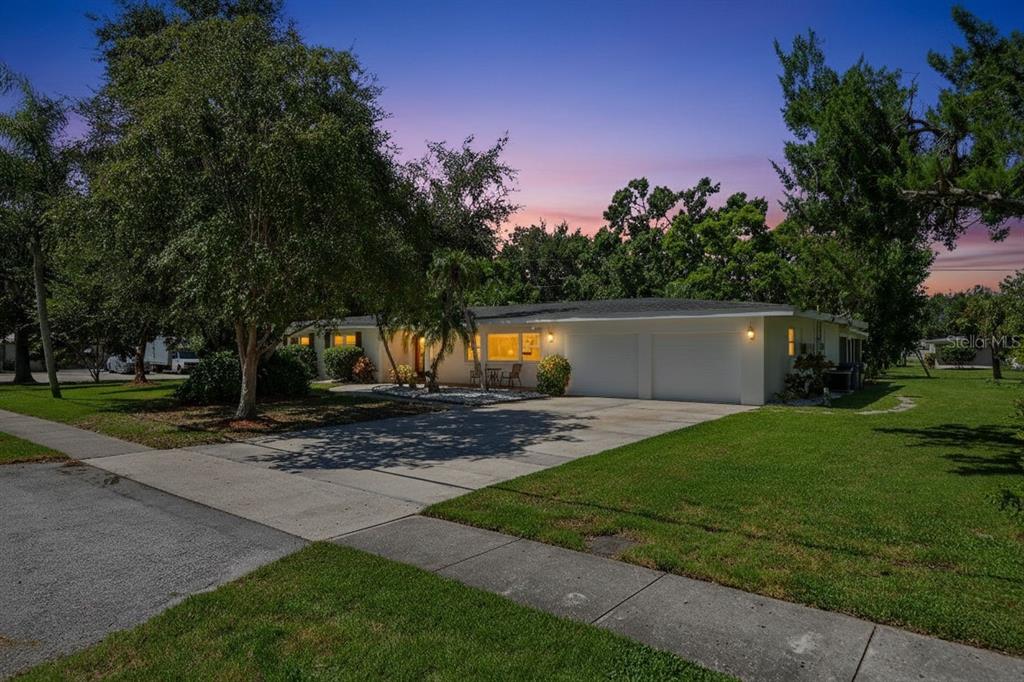 A single-story house with a two-car garage and a concrete driveway at sunset — 4808 RIVERWOOD AVENUE, SARASOTA, FL