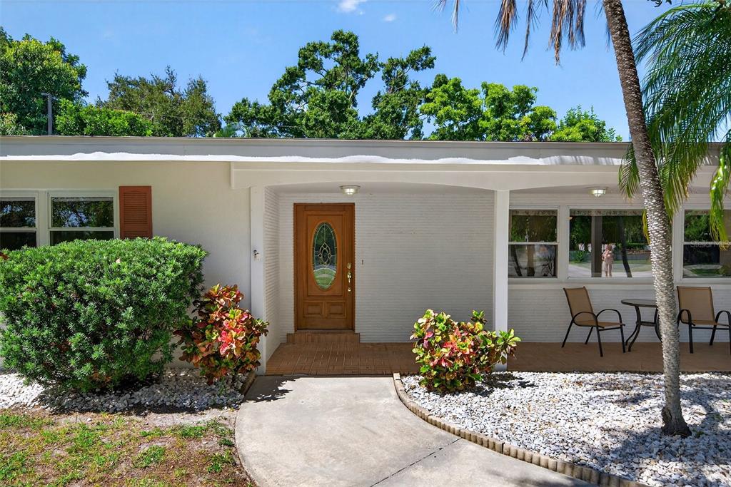 A single-story house exterior features a white brick facade, a wooden front door, and a porch — 4808 RIVERWOOD AVENUE, SARASOTA, FL