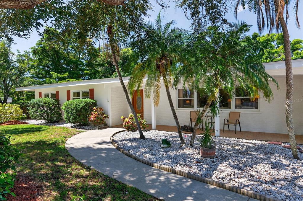 A single-story white house features a curved walkway, palm trees, and a gravel front yard — 4808 RIVERWOOD AVENUE, SARASOTA, FL