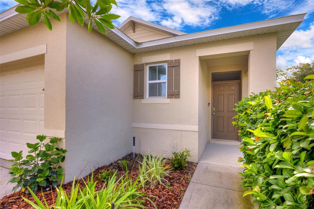 A beige house exterior features a garage, a single window with shutters, and a front entrance — 227 DUKE DRIVE, DELAND, FL