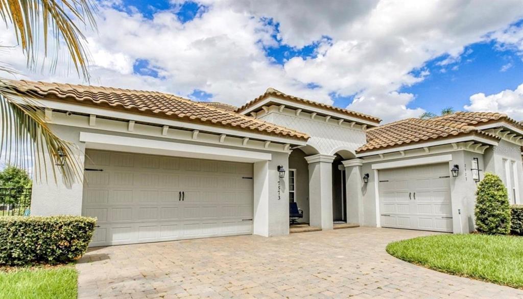 A single-story house features a light-colored stucco exterior, a tiled roof, and a three-car garage — 7573 GREEN MOUNTAIN WAY, WINTER GARDEN, FL