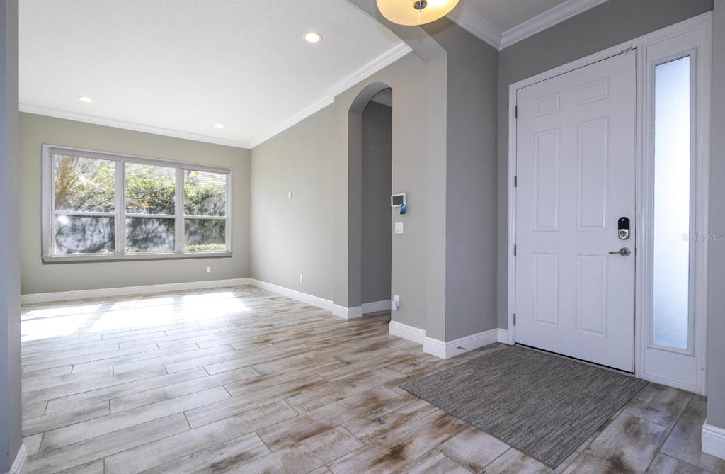 An entryway with light wood-look tile flooring, gray walls, and a white front door — 7573 GREEN MOUNTAIN WAY, WINTER GARDEN, FL