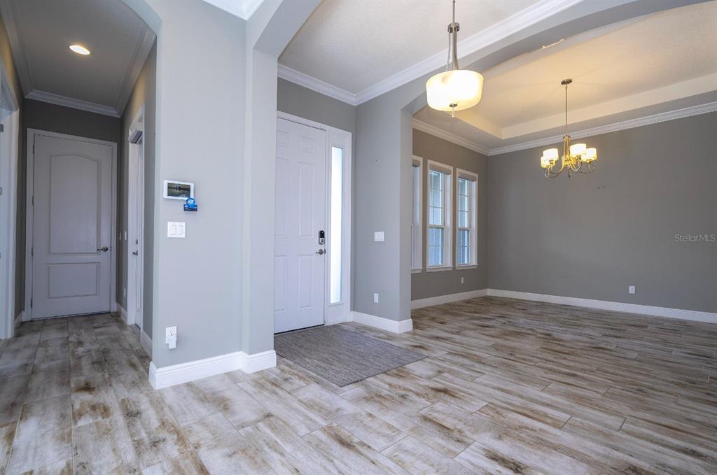 An entryway with light wood-look tile flooring, gray walls, and a white front door — 7573 GREEN MOUNTAIN WAY, WINTER GARDEN, FL