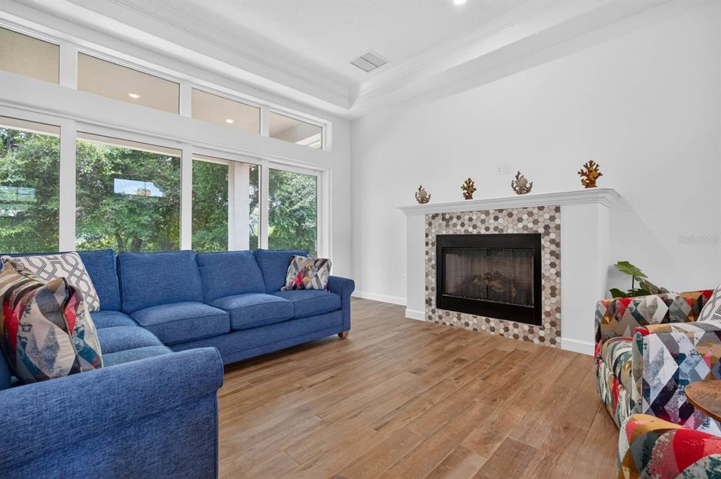 A living room with a blue sectional sofa, patterned armchair, and a tiled fireplace — 46 NEW LEATHERWOOD DRIVE, PALM COAST, FL