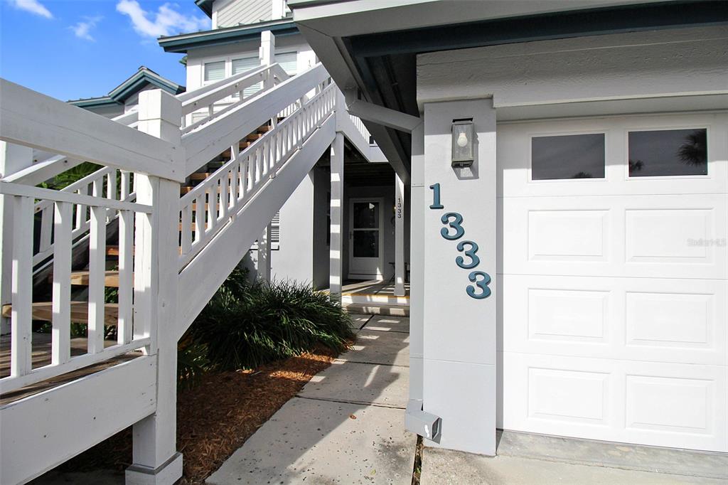 A white exterior staircase leads to an entrance next to a garage with house numbers — 1333 SIESTA BAYSIDE DRIVE UNIT 1333-D, SARASOTA, FL