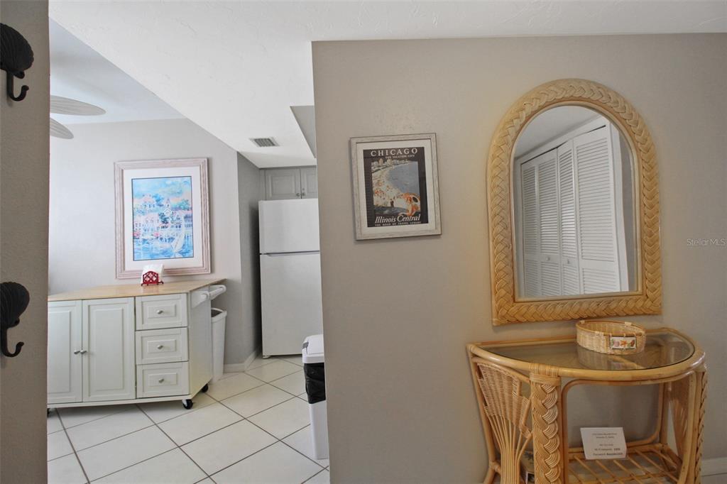 A kitchen area with white cabinets and tile floors sits next to a hallway with furniture — 1333 SIESTA BAYSIDE DRIVE UNIT 1333-D, SARASOTA, FL