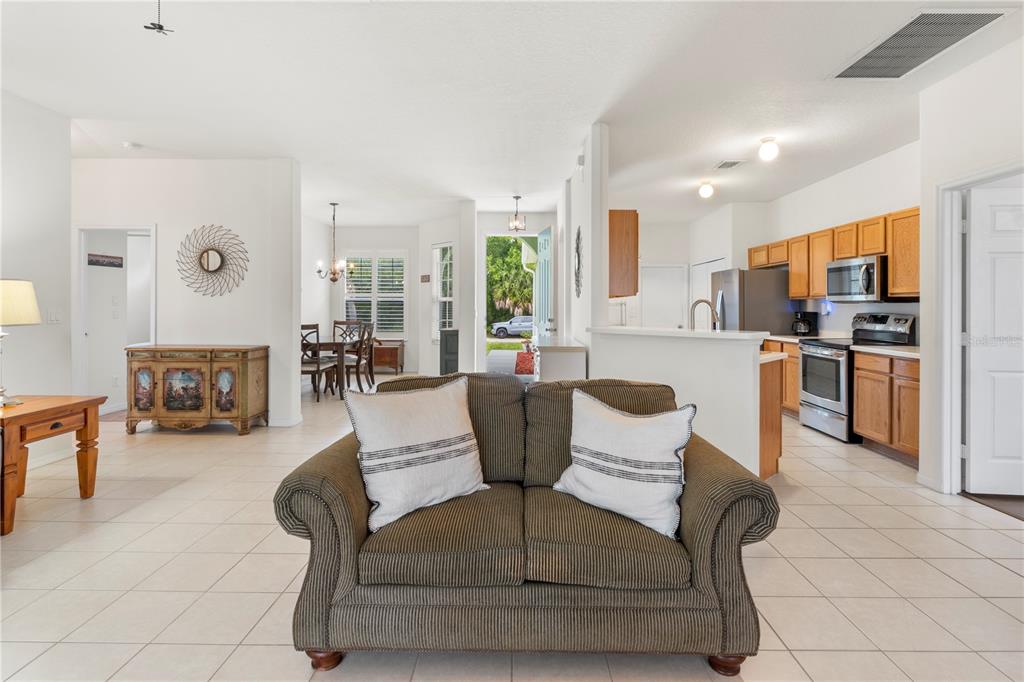 A living room with a striped sofa faces an open kitchen and a dining area — 8316 106TH AVENUE, VERO BEACH, FL