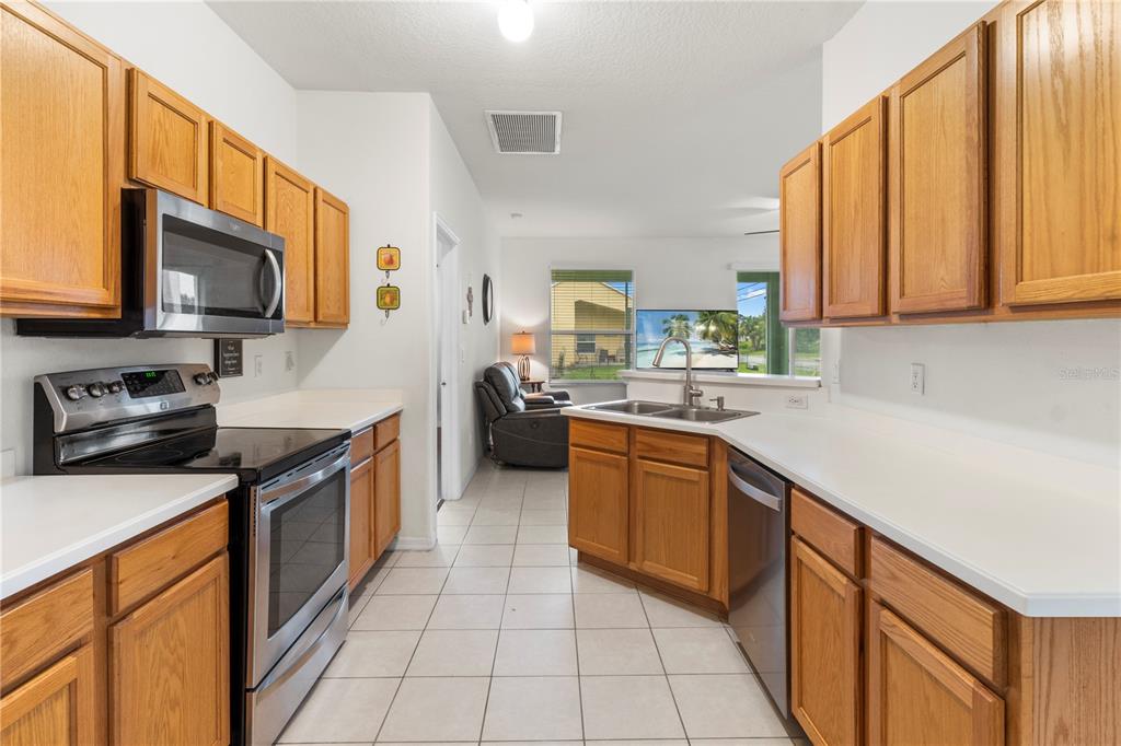 A kitchen with oak cabinets, stainless steel appliances, white countertops, and tile flooring — 8316 106TH AVENUE, VERO BEACH, FL