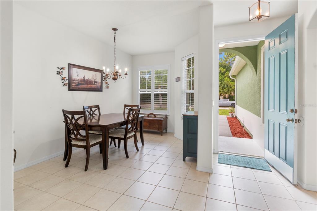 A dining area with tile floors, a wooden table, and an open door to the exterior — 8316 106TH AVENUE, VERO BEACH, FL