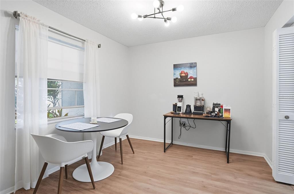A dining area features a round table with two chairs and a coffee station console — 1715 BELLEAIR FOREST DRIVE UNIT A, BELLEAIR, FL