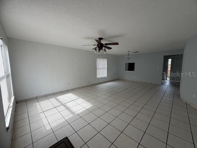 An empty living room features white tile flooring, a ceiling fan, and a large window — 1610 LITTLE RIVER DRIVE UNIT 20, ORLANDO, FL