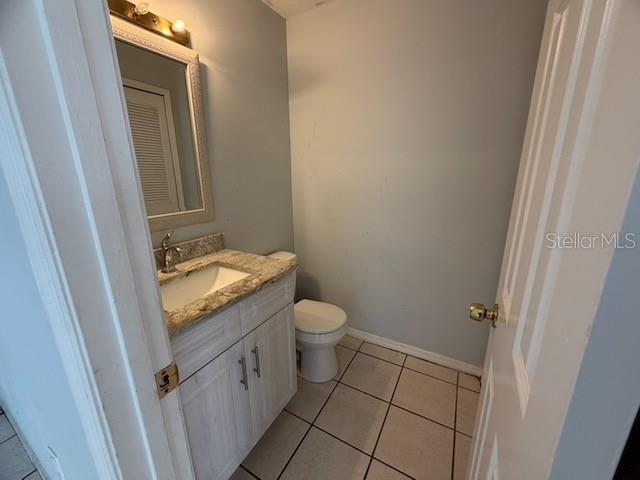 A small bathroom features a vanity with a granite countertop, a mirror, and a toilet — 1610 LITTLE RIVER DRIVE UNIT 20, ORLANDO, FL