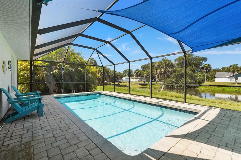 A rectangular swimming pool sits on a paved patio inside a screened-in pool enclosure — 2240 GENTIAN ROAD, VENICE, FL