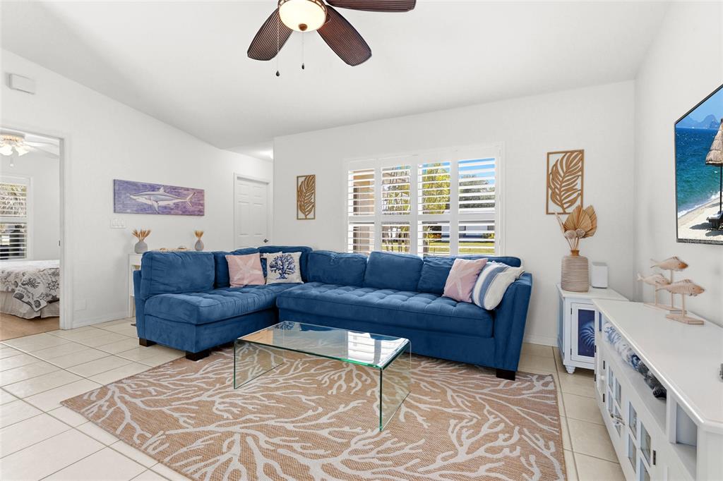 A living room features a blue sectional sofa, a glass coffee table, and a coral-patterned rug — 2240 GENTIAN ROAD, VENICE, FL