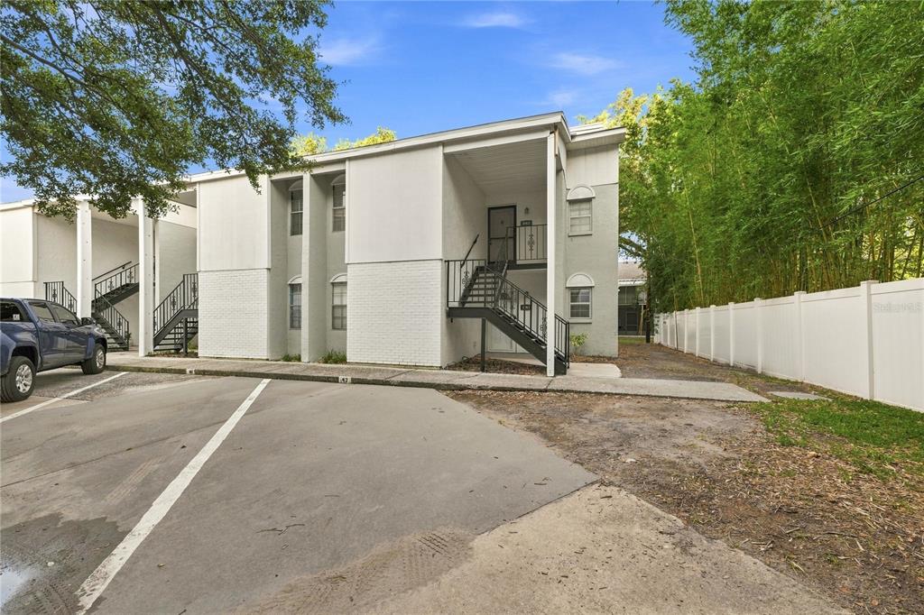 A two-story apartment building with exterior staircases, white siding, and a paved parking area — 3807 N OAK DRIVE UNIT D41, TAMPA, FL