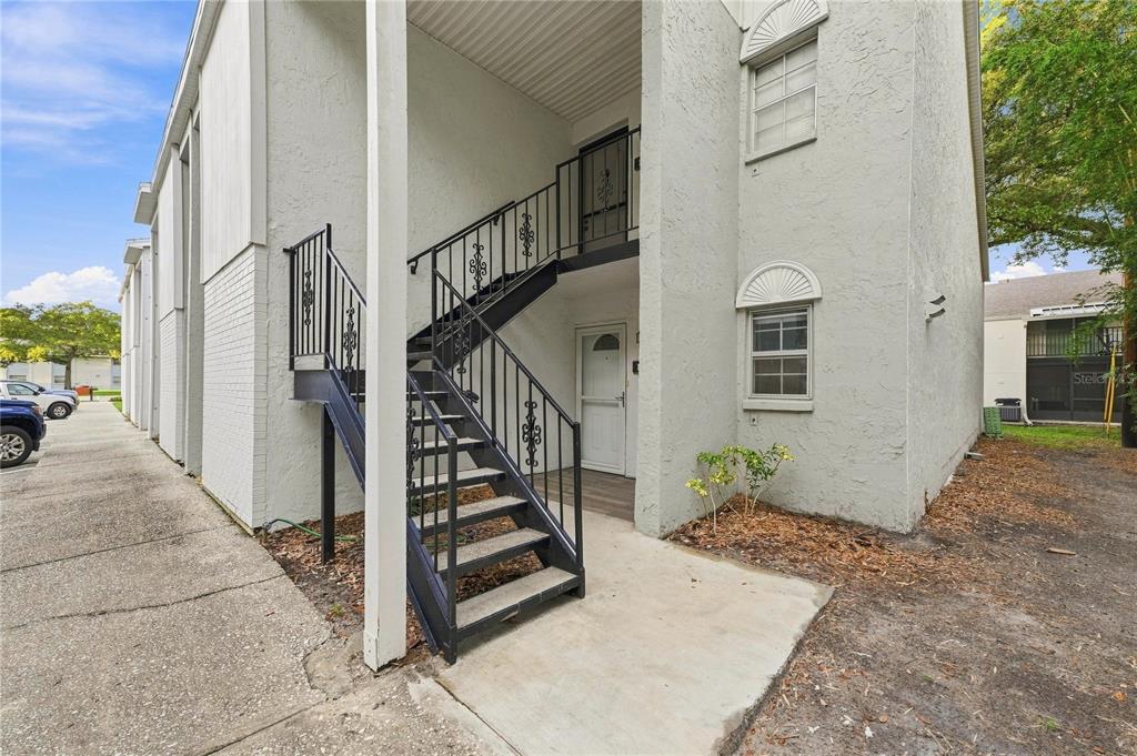 An exterior view of a two-story apartment building with a metal staircase leading upstairs — 3807 N OAK DRIVE UNIT D41, TAMPA, FL