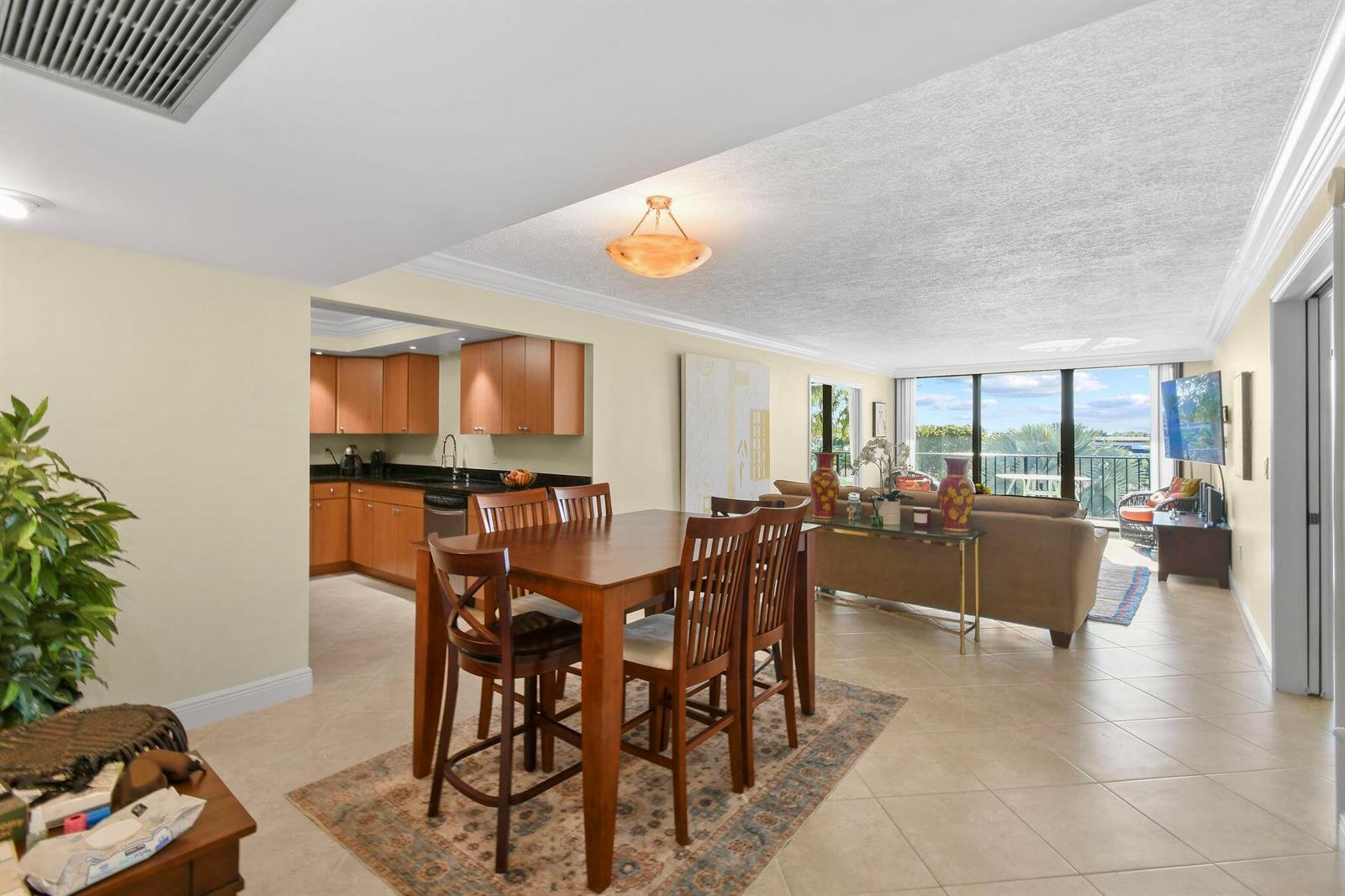 An open-concept dining area and living room with tile flooring, wooden furniture, and a kitchen — 3460 S Ocean Boulevard # 2090, Palm Beach FL 33480, PALM BEACH, FL