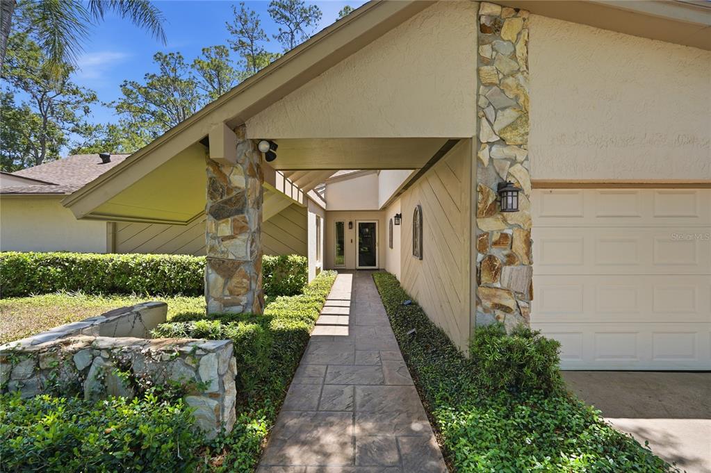 A stone-paved walkway leads to the front entrance of a house with stone pillars — 3071 BOLT DRIVE, PALM HARBOR, FL