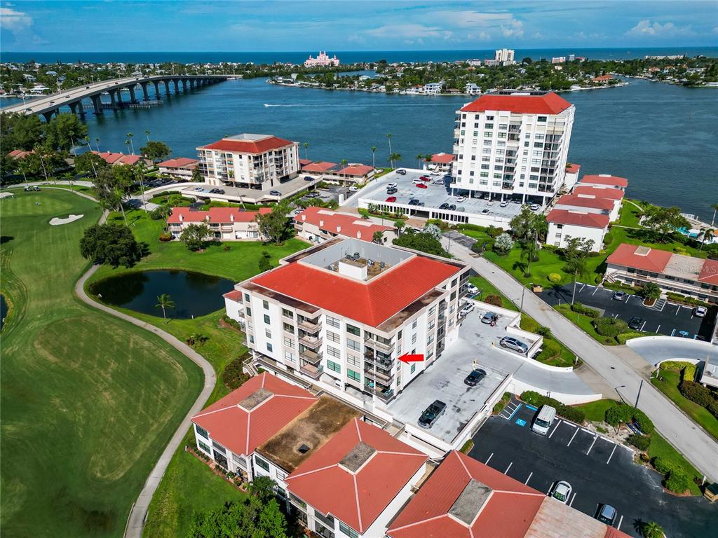 An aerial view shows a multi-story residential building with a red roof near water — 6210 SUN BOULEVARD UNIT 506, ST PETERSBURG, FL
