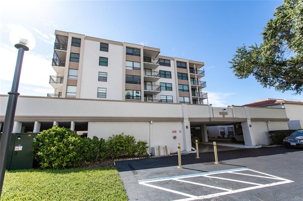 A multi-story apartment building features balconies and a ground-level parking garage entrance — 6210 SUN BOULEVARD UNIT 506, ST PETERSBURG, FL