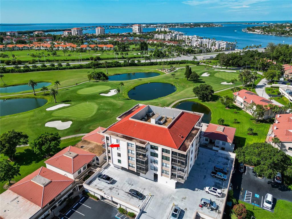 An aerial view shows a multi-story apartment building with a red roof near a golf course — 6210 SUN BOULEVARD UNIT 506, ST PETERSBURG, FL