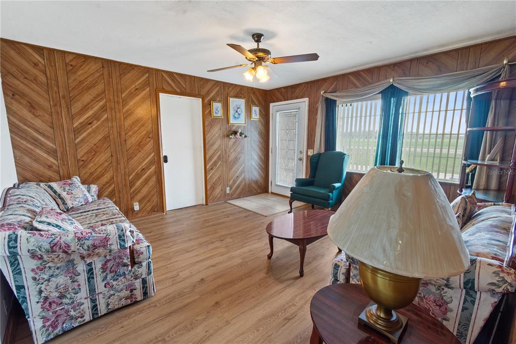 A living room features wood-paneled walls, floral sofas, a coffee table, and wood-look flooring — 245 ALTURAS ROAD, BARTOW, FL