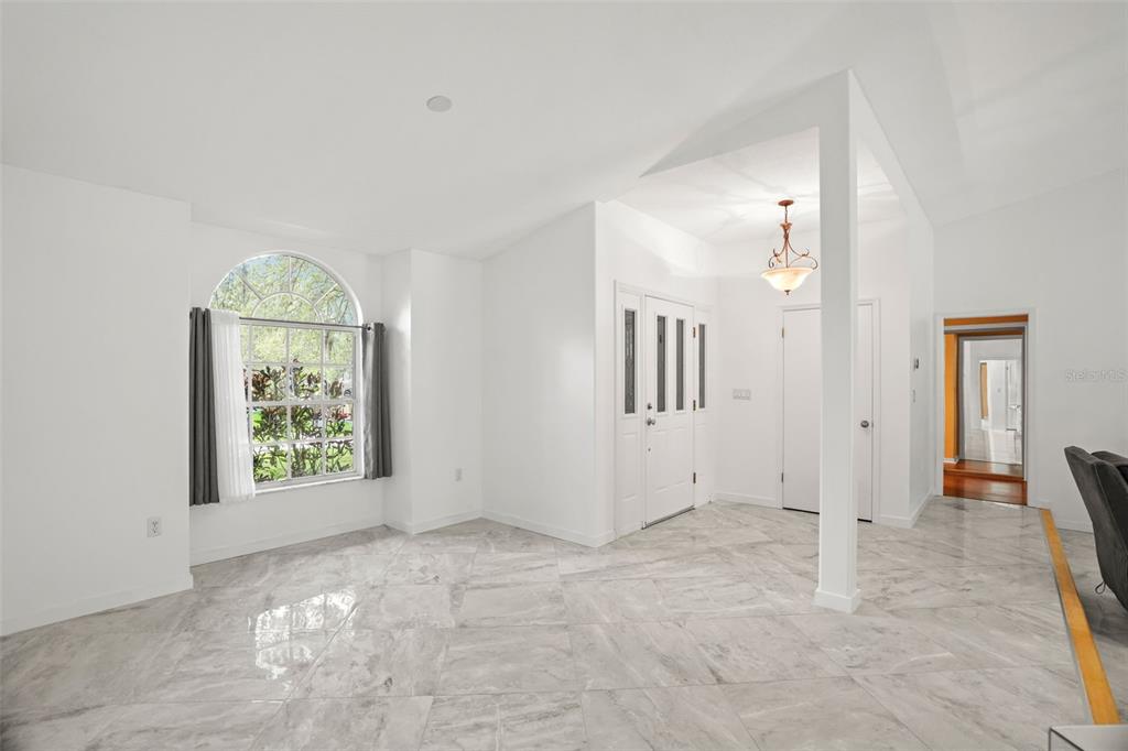 An entryway with white walls, light gray marble-look tile flooring, and a large arched window — 8020 MOONLIGHT LANE, NEW PORT RICHEY, FL