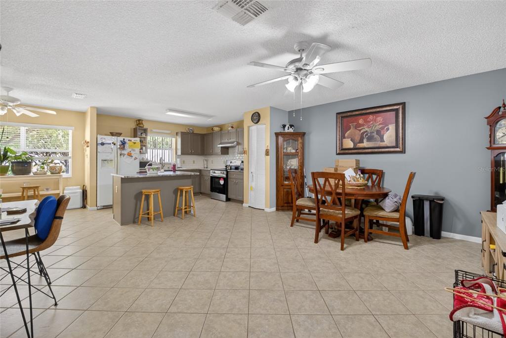 A kitchen and dining area with tile floors, gray cabinets, and a ceiling fan — 9661 SW 95TH COURT UNIT B, OCALA, FL