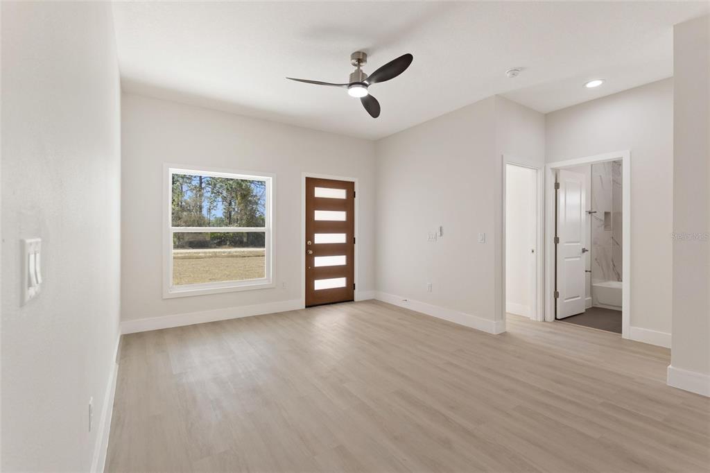 A bedroom with light wood-look flooring, a ceiling fan, a window, and an exterior door — 3970 LAGUNA DRIVE, INDIAN LAKE ESTATES, FL