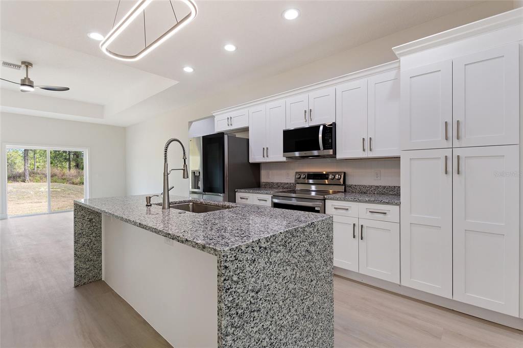 A kitchen features white cabinets, granite countertops, a center island, and stainless steel appliances — 3970 LAGUNA DRIVE, INDIAN LAKE ESTATES, FL