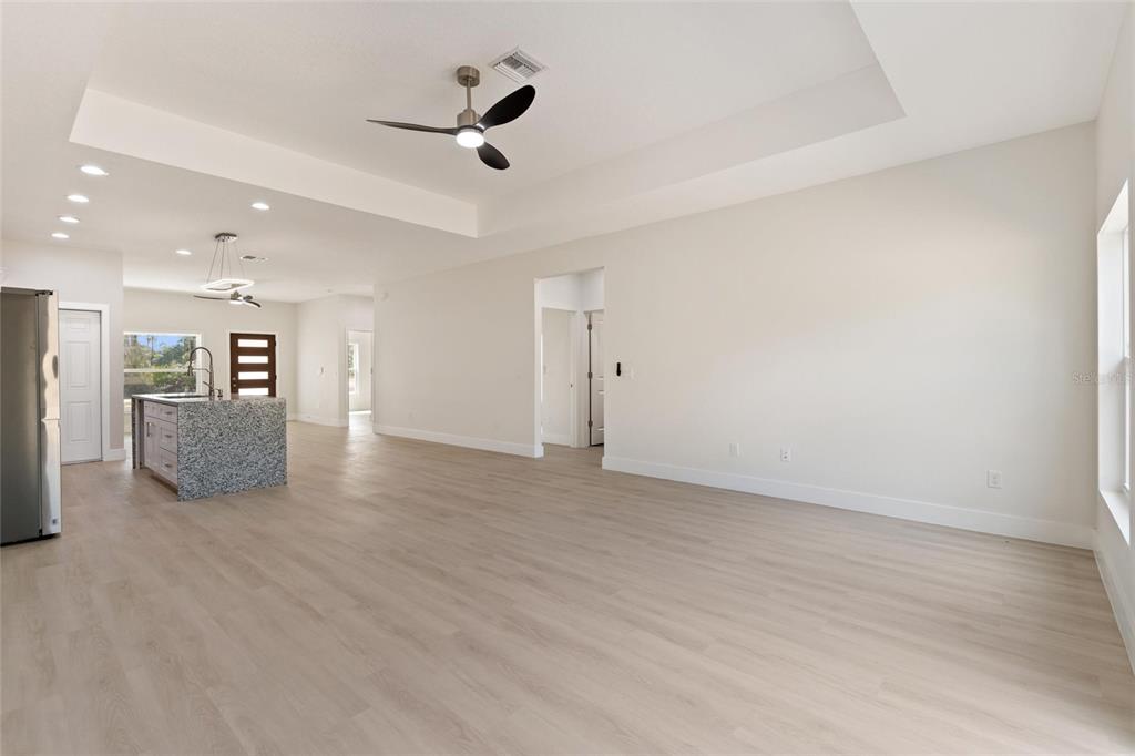 An open-concept living area features light wood-look flooring, a tray ceiling, and a kitchen island — 3970 LAGUNA DRIVE, INDIAN LAKE ESTATES, FL