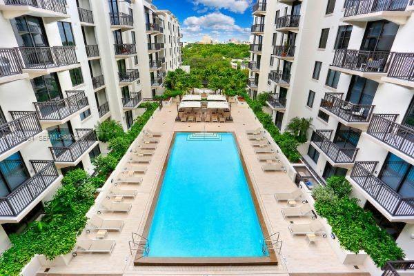 An aerial view of a rectangular swimming pool surrounded by lounge chairs between apartment buildings — 301 Altara Ave # 805, Coral Gables FL 33146, CORAL GABLES, FL