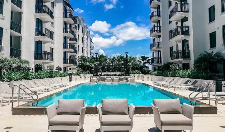 An outdoor swimming pool is surrounded by lounge chairs and multi-story apartment buildings — 301 Altara Ave # 805, Coral Gables FL 33146, CORAL GABLES, FL