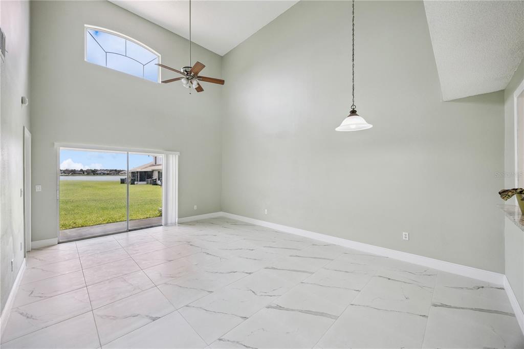 A spacious room with high ceilings, white marble-look tile floors, and a sliding glass door — 14451 BAY ISLE DRIVE, ORLANDO, FL