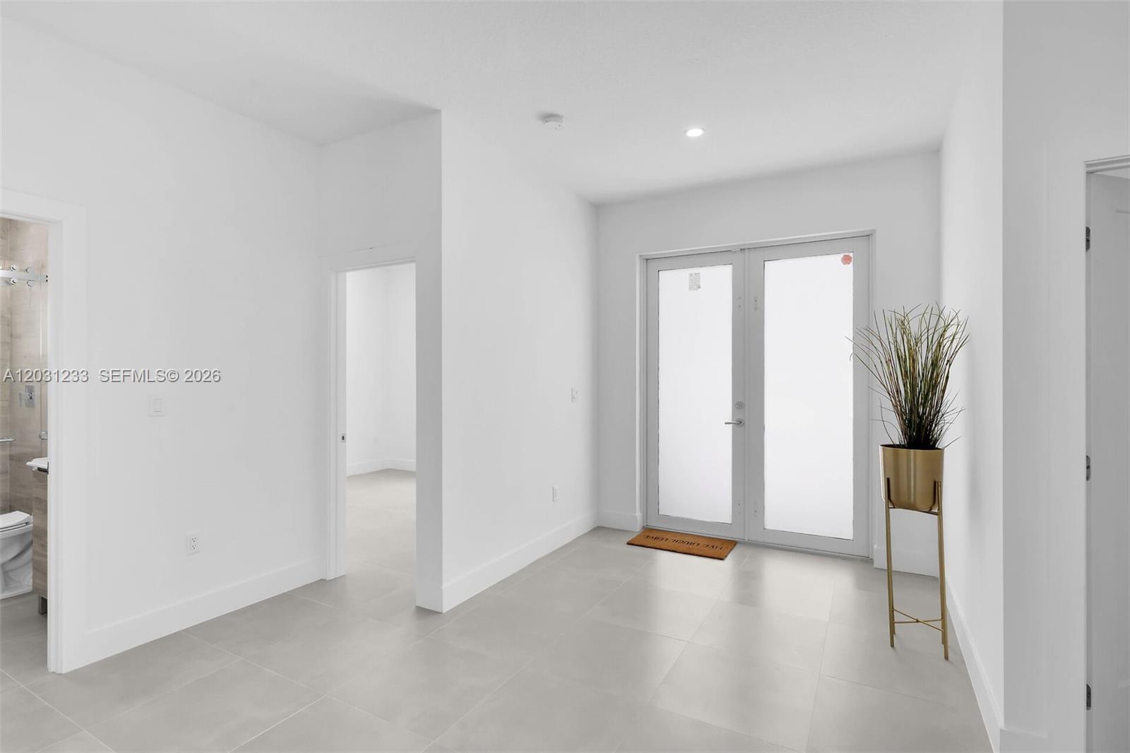 A bright, minimalist room features white walls, light tile flooring, and double glass doors — 21 Tina Pl, Key Largo FL 33037, KEY LARGO, FL