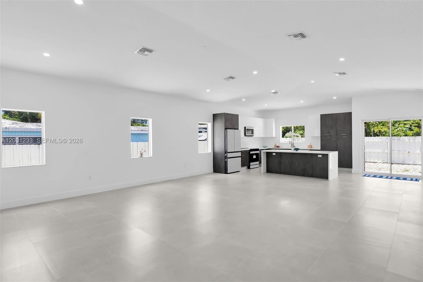 A modern, open-concept kitchen features dark cabinetry, white countertops, and light tile flooring — 21 Tina Pl, Key Largo FL 33037, KEY LARGO, FL