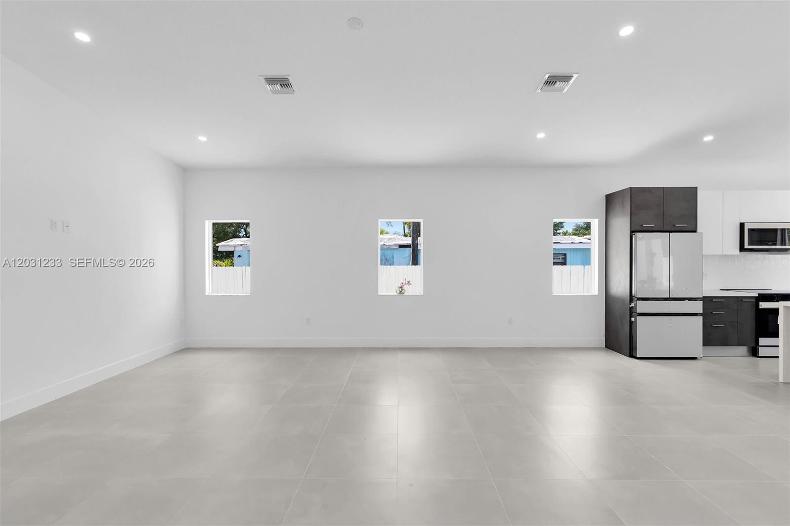 A modern, minimalist room features white walls, large light-colored floor tiles, and a kitchen area — 21 Tina Pl, Key Largo FL 33037, KEY LARGO, FL